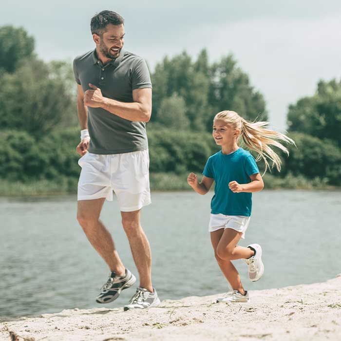 Dad jogging with his daughter on the beach