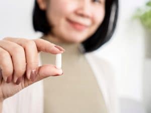 Image of a woman holding a glutathione supplement